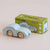 A wooden toy car in a pale mint green color with natural wood wheels, shown next to its green and yellow 'Le Toy Van' GT15 Jude limited edition packaging box on a light beige background.