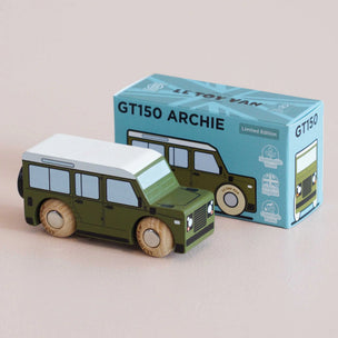 Green toy van with white roof next to its packaging on a beige background