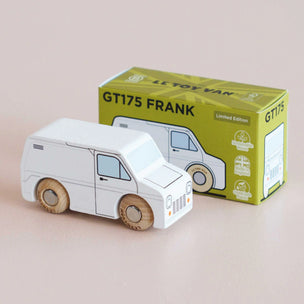 White toy van next to its green box packaging on a beige background
