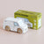 White toy van next to its green box packaging on a beige background