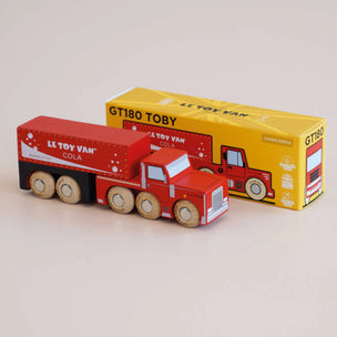a red toy fire truck pakred up next to its box from a side angle view 