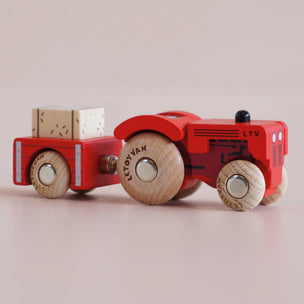 Red toy truck with wooden wheels on a light beige background