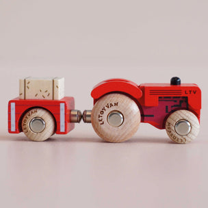 Wooden toy tractor with a trailer on a beige background