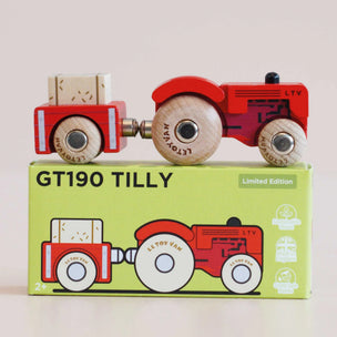 Wooden toy truck with red body and white wheels on top of its packaging box.
