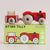 Wooden toy truck with red body and white wheels on top of its packaging box.