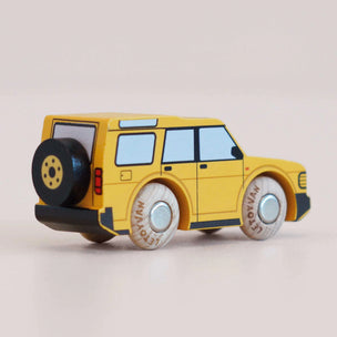 Yellow toy car with black and white wheels on a beige background