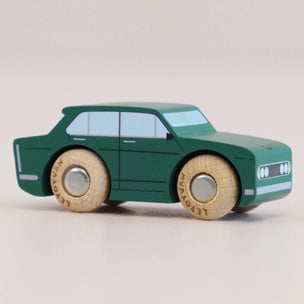 Green toy car with wooden wheels on a light gray background