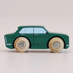 Green toy car with wooden wheels on a light beige background