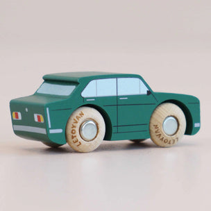 Green toy car with wooden wheels on a beige background