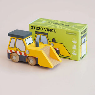 Wooden toy bulldozer in front of its packaging box on a beige background