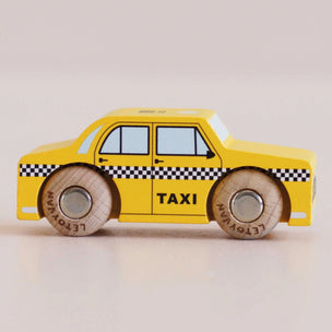 Toy taxi car with checkered pattern on wheels against a beige background