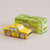 Yellow toy taxi car next to its green box packaging on a beige background