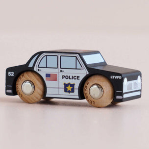 Wooden toy police car with American flag and police insignia on a beige background