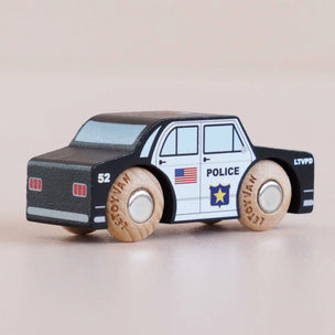 Wooden toy police car with American flag and 'POLICE' text on a beige background