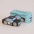 Wooden toy police car with Le Toy Van packaging on a beige background