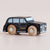 a black taxi toy car sideways with. a beige background 