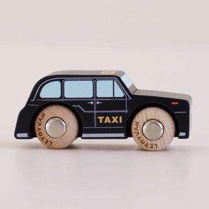 A wooden toy taxi car with a black body, light blue windows, and natural wood wheels, shown on a plain light beige background.