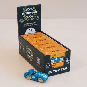 A display box of Le Toy Van limited edition toy cars, with a single blue wooden toy car placed in front on a light beige background.