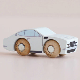 Wooden toy car with a white body and brown wheels on a beige background