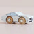 Wooden toy car with a white body and brown wheels on a beige background