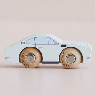 A wooden toy car with a pale blue body and natural wood wheels, shown in profile against a soft beige background. The wheels are branded with the text 'LETOISIAN'.