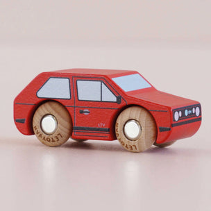 Red toy car with wooden wheels on a light beige background