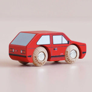 Red toy car with wooden wheels on a beige background