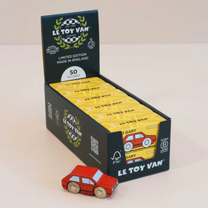 A display box of Le Toy Van limited edition toy cars, with a small red wooden car in front on a light beige background.
