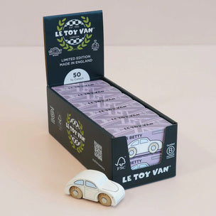 A display box of Le Toy Van 'Limited Edition' collectible wooden toy cars, with one white wooden car placed in front on a light beige background.