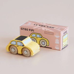 Yellow toy car next to its packaging box on a beige background