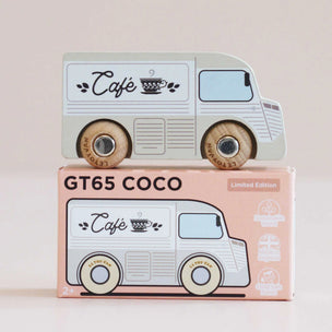 A wooden toy coffee truck with light green and white panels and natural wood wheels, displayed on top of its pink packaging box labeled 'GT65 COCO' and 'Limited Edition'.