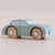 A small wooden toy car in a dusty light blue-green color with natural wood wheels and silver hubcaps, photographed on a plain light beige background.