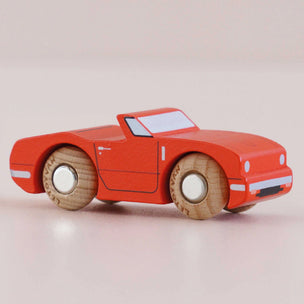 Red toy car with wooden wheels on a beige background