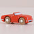 Red toy car with wooden wheels on a beige background