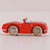 Red toy car with wooden wheels on a light pink background