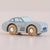 A small toy car with a matte light gray body and natural wood wheels, photographed on a soft warm beige background.