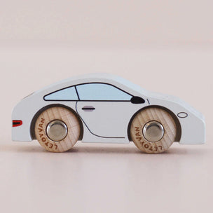 A side-view wooden toy car with a white body, light blue window, and natural wood wheels engraved with the brand name 'LET'S PLAY'.