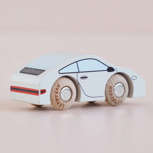 Wooden toy car with a white body and wooden wheels on a beige background