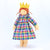 Doll wearing a colorful plaid dress and yellow crown on a white background