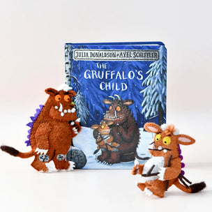Book titled 'The Gruffalo's Child' with plush toys of a fox and a gruffalo on a white background