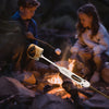 Two children roasting marshmallows over a campfire with a Marshmallow Roaster tool.