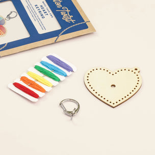 Wooden heart-shaped keyring kit with colorful strings and a metal keyring on a light background.