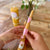 Two hands holding a set of beeswax candles with floral designs on a wooden surface.