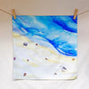 Artistic depiction of a beach scene with blue water and sand, hanging on a line.