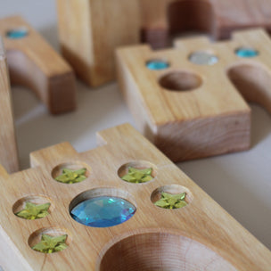 Wooden puzzle pieces with embedded colorful stones on a light surface