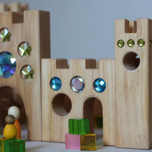 Wooden building blocks with colorful gemstones on a plain background