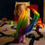Child playing with a rainbow-colored cape in a playroom.