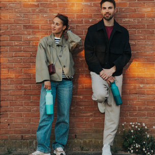 Two people leaning against a brick wall with a warm glow.