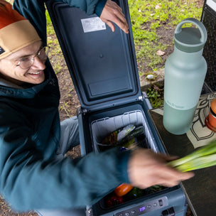 Person opening a cooler with food items including eggs and vegetables, with a water bottle nearby.