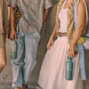 Four people walking together, each carrying different items like a red bag, green water bottle, and white shoes.